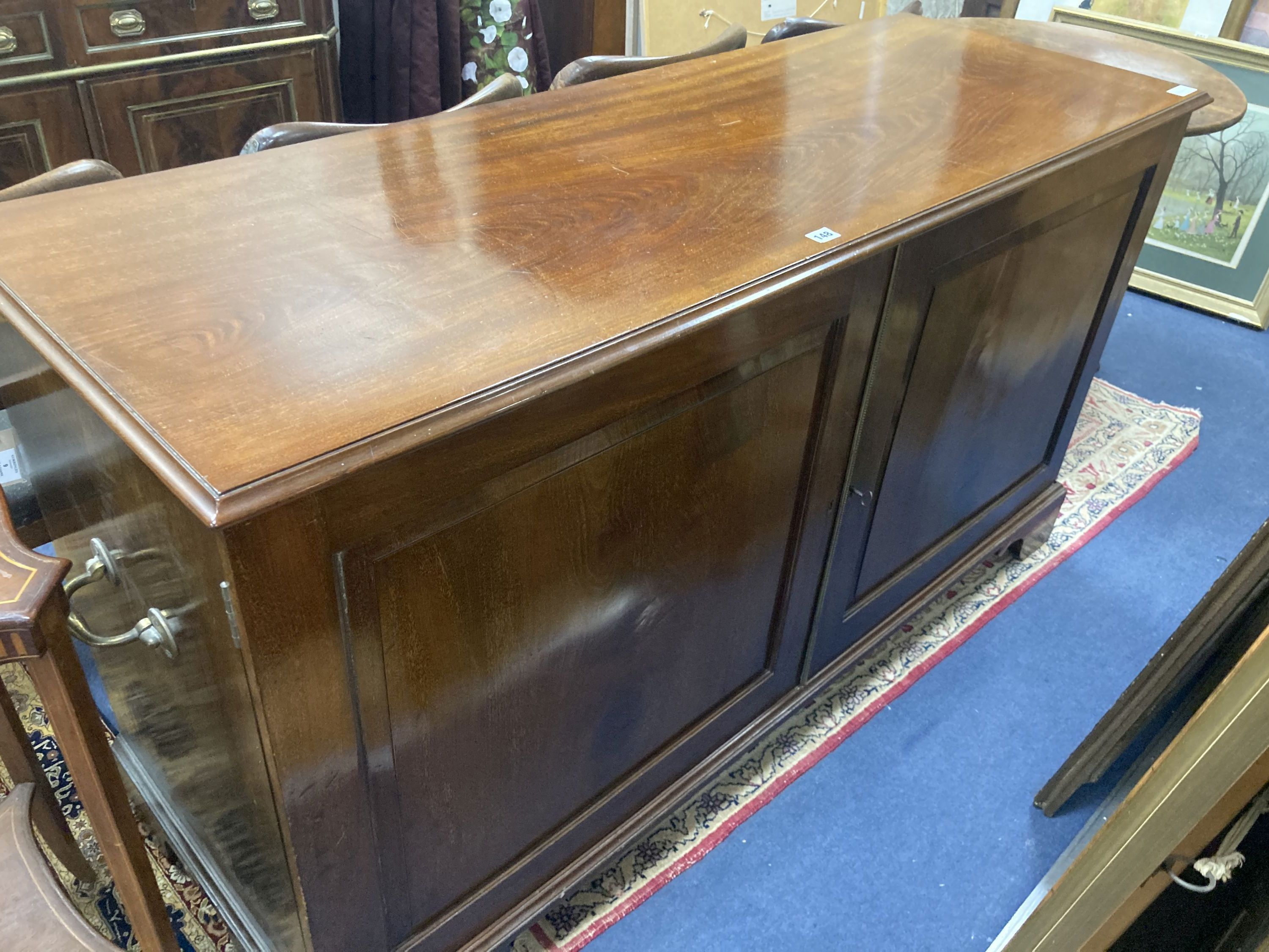 A late Victorian mahogany cupboard, fitted with a pair of fielded panelled doors, flanked by brass side carrying handles